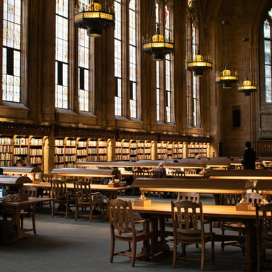 Grand Gothic reading room with tall windows and long wooden tables