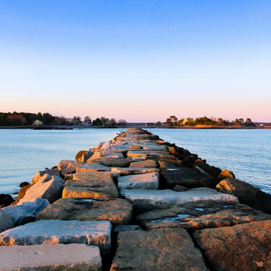 Stone causeway stretching into calm water at dusk
